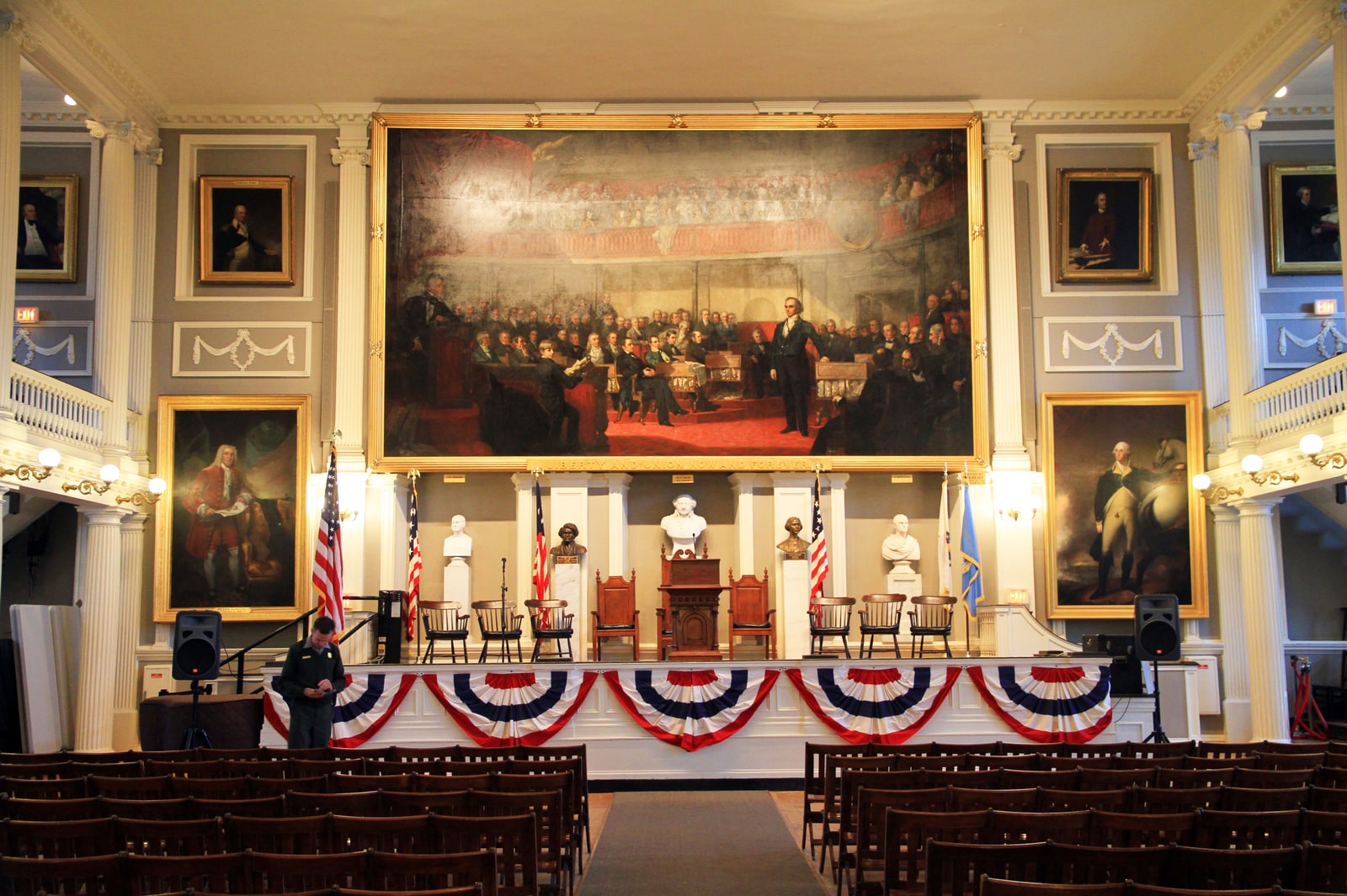 The historic Great Hall inside Faneuil Hall, with portraits, columns and an American history painting